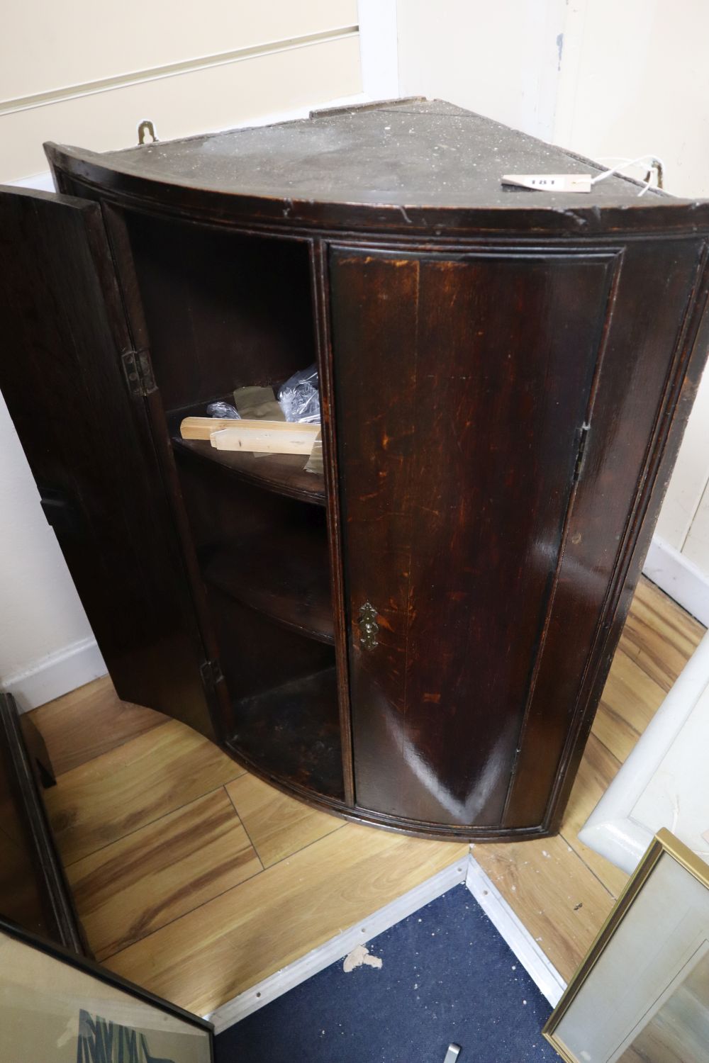 A George III oak bow-fronted hanging corner cupboard